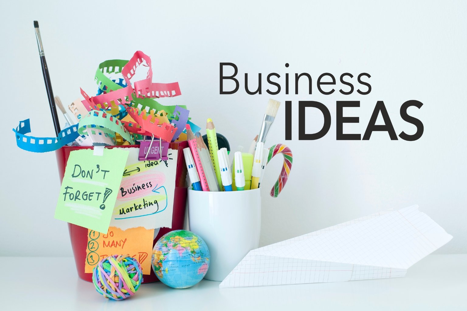 “Colorful stationery, notes, globe and paper airplane with text Best Online Business Ideas on white background.”